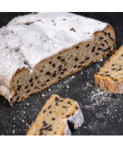 Saftiger Schoko-Stollen mit vielen Schokostückchen und einer Schicht Puderzucker, angeschnitten und dekorativ präsentiert.