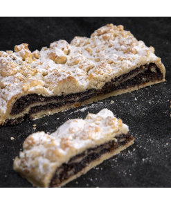 Frischer Mohnstriezel mit Streuseln und Puderzucker auf dunklem Untergrund, angeschnitten und detailliert sichtbar.